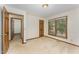 Empty bedroom with carpeted floors, wood trim, and natural light from a window, leading to another room at 8409 Crowder Rd, Raleigh, NC 27603