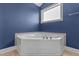Bright, white jacuzzi bathtub nestled under a window in a luxurious bathroom with blue walls at 870 Kentucky Derby Ln, Lillington, NC 27546