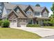 Stately two-story home featuring a stone facade, well-manicured lawn, and a spacious three-car garage at 870 Kentucky Derby Ln, Lillington, NC 27546