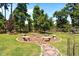 Charming backyard fire pit area with stone benches, surrounded by lush greenery, ideal for outdoor gatherings at 870 Kentucky Derby Ln, Lillington, NC 27546