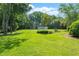 Expansive backyard with lush lawn, mature trees, outbuilding, and fountain at 8733 Crowder Rd, Raleigh, NC 27603
