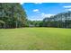 Wide open backyard with plenty of green grass bordered by tall trees and landscaping at 8733 Crowder Rd, Raleigh, NC 27603
