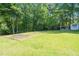 Grassy backyard featuring a potential sand volleyball court next to a shady wooded area at 8733 Crowder Rd, Raleigh, NC 27603