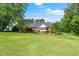 Sprawling backyard with lush lawn, mature trees, and rear view of home with fountain at 8733 Crowder Rd, Raleigh, NC 27603