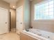 Bright bathroom featuring a jacuzzi tub under glass block window, and a separate walk-in shower at 91 E Walker Woods Ln, Clayton, NC 27527