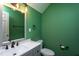 Stylish half-bathroom with a sleek vanity, modern fixtures, and a vibrant green accent wall at 1009 Open Field Dr, Garner, NC 27529