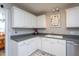 A kitchen offers white cabinetry, gray countertops, and neutral flooring with views into the dining area at 1009 Open Field Dr, Garner, NC 27529