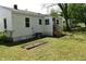Exterior view of the backyard with a small garden bed, wooden stairs, and a glimpse of nature at 102 Allen St, Graham, NC 27253
