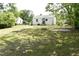 The backyard of this home features mature trees, grassy areas, and a view of the back of the house at 102 Allen St, Graham, NC 27253