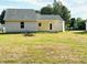 Backyard view showcasing the home's exterior and well-maintained lawn with mature trees at 107 Earnest Way, Kenly, NC 27542
