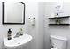 Bright half-bathroom featuring a wall-mounted sink, toilet, dark accents, and decorative shelves at 110 Stoney Dr, Durham, NC 27703