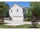 A two-car garage with a concrete driveway, lush foliage and trees and gray vinyl siding and green roof at 110 Stoney Dr, Durham, NC 27703