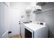 A functional laundry room with a washer, dryer, shelving, and a white door at 110 Stoney Dr, Durham, NC 27703