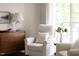 Comfortable sitting area features plush white chairs, a wood accent table, and natural light from the large window at 110 Stoney Dr, Durham, NC 27703