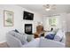 Bright living room with fireplace, hardwood floors, modern furniture, and a large window with natural light at 110 Stoney Dr, Durham, NC 27703