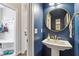 Stylish powder room with navy blue walls, pedestal sink, and decorative gold framed mirror at 113 Old Ballentine Way, Holly Springs, NC 27540