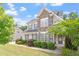 Charming two-story home featuring a stone facade, gray siding, manicured lawn, and lush landscaping at 113 Old Ballentine Way, Holly Springs, NC 27540