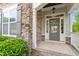 Inviting front entrance featuring stone accents, decorative wreath, and stylish gray door at 113 Old Ballentine Way, Holly Springs, NC 27540