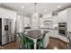 Well-lit kitchen features white cabinets, stainless steel appliances, large island with green seating at 113 Old Ballentine Way, Holly Springs, NC 27540