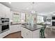 Well-appointed kitchen with island, stainless appliances, white cabinets and view to the living room at 113 Old Ballentine Way, Holly Springs, NC 27540