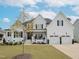 Inviting white brick home with covered porch, rocking chairs, black shutters, and meticulously landscaped yard at 1180 Duke Farm Dr, Wake Forest, NC 27587