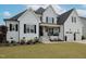 Charming white brick home featuring black shutters, a covered porch, and well-manicured lawn at 1180 Duke Farm Dr, Wake Forest, NC 27587