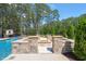Backyard fire pit made of stone sitting adjacent to the pool in a wooded backyard at 120 Lu Tom Ln, Wendell, NC 27591