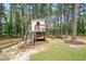 Wooden playhouse with a slide, swing, and climbing stairs in a grassy, fenced yard at 120 Lu Tom Ln, Wendell, NC 27591