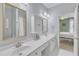 Bright bathroom with double sinks, white cabinets, gold hardware and trim, and view to bedroom at 1201 Red Beech Ct, Raleigh, NC 27614