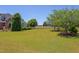 Spacious backyard featuring manicured lawn, mature trees, and distant view at 130 Skipwith Dr, Wendell, NC 27591
