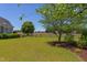 Spacious fenced backyard featuring a lush green lawn, mature trees and landscaped beds under a clear blue sky at 130 Skipwith Dr, Wendell, NC 27591