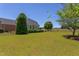Spacious fenced backyard featuring a lush green lawn, mature trees, and a well-maintained garden surrounding the house at 130 Skipwith Dr, Wendell, NC 27591