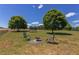 Landscaped backyard featuring a fire pit, seating area, mature trees, and a trampoline at 130 Skipwith Dr, Wendell, NC 27591