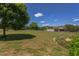 Spacious grassy backyard featuring scattered trees, shrubs, and a view of the home and garage structures at 130 Skipwith Dr, Wendell, NC 27591
