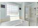 Bright bathroom featuring a soaking tub and a separate glass-enclosed shower with decorative touches at 130 Skipwith Dr, Wendell, NC 27591