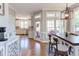 Open dining area with rustic wood table, modern light fixture, and view to the kitchen and outdoor seating area at 130 Skipwith Dr, Wendell, NC 27591