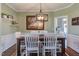 Light-filled dining room with an elegant chandelier, wainscoting and a rustic table at 130 Skipwith Dr, Wendell, NC 27591
