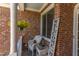Charming covered front porch with brick, white wicker furniture and a hanging floral arrangement at 130 Skipwith Dr, Wendell, NC 27591