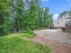 The backyard has green grass, many trees, and a gravel area for extra parking at 1313 Ridge Rd, Raleigh, NC 27607