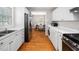 Spacious kitchen layout leading to dining area is equipped with modern stainless appliances and white cabinets at 1313 Ridge Rd, Raleigh, NC 27607
