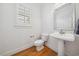 Elegant powder room featuring a pedestal sink, modern toilet, wood floors, and window with plantation shutters at 1328 Palace Garden Way, Raleigh, NC 27603