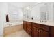Bathroom with a double sink vanity, large mirror, bathtub, and tile flooring; windows with plantation shutters at 1328 Palace Garden Way, Raleigh, NC 27603