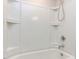 Bright bathtub with a shower head featuring storage shelves and tile at 1380 Channing Park Cir, Cary, NC 27519