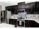 Close-up of kitchen showcasing dark cabinets, mosaic backsplash, stainless steel appliances and countertops at 1424 Forest Fern Ln, Fuquay Varina, NC 27526