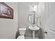Powder room with pedestal sink, decorative mirror, and modern light fixture at 1605 Silo Point Dr, Wake Forest, NC 27587