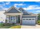 Charming home featuring a two-car garage, covered porch with stone accents and beautifully maintained lawn at 1665 Wilde Bnd, Apex, NC 27523