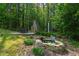 Serene backyard featuring a stone fireplace, water feature, and lush landscaping, creating a peaceful retreat at 197 Boxwood Dr, Pittsboro, NC 27312