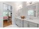 Elegant bathroom featuring dual vanities, white cabinets, and a view to the main bedroom at 197 Boxwood Dr, Pittsboro, NC 27312