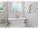 Elegant soaking tub with chrome fixtures, framed by marble tile and a bright window at 197 Boxwood Dr, Pittsboro, NC 27312