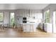 Bright, modern kitchen features white cabinets, stainless steel appliances, an island, and hardwood floors with ample natural light at 208 Byrum St # 5, Cary, NC 27511